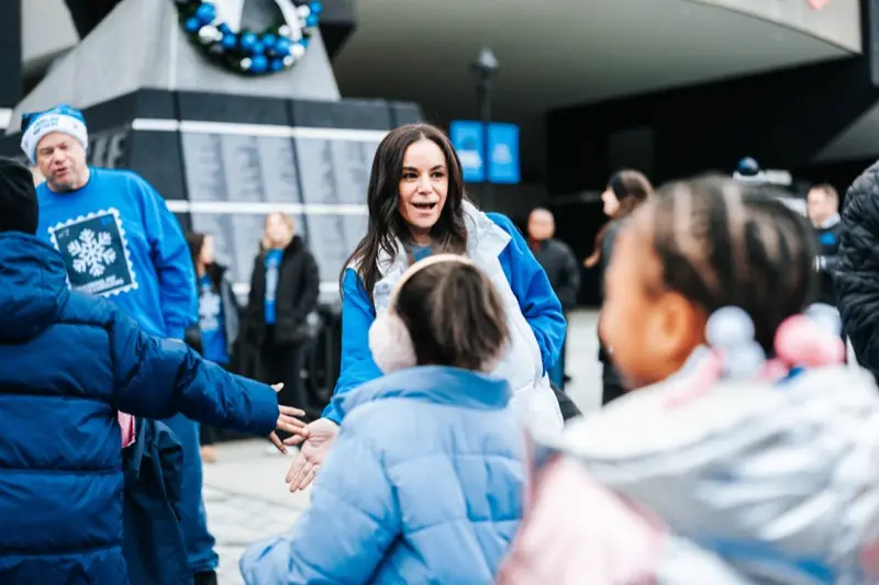 Volunteers in blue sweaters give high-fives to arriving students