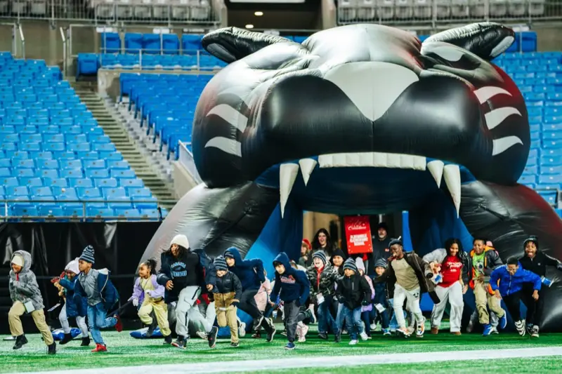 Students run onto the field through a giant inflatable panther tunnel